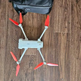 Mini drone with four red-bladed propellers and light blue body