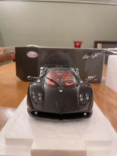 Black diecast sports car model in packaging, front view with clear display window.