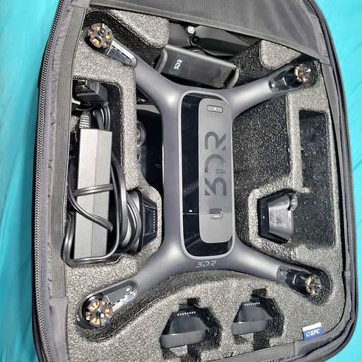 Gray drone in a hard carry case with propellers and accessory parts