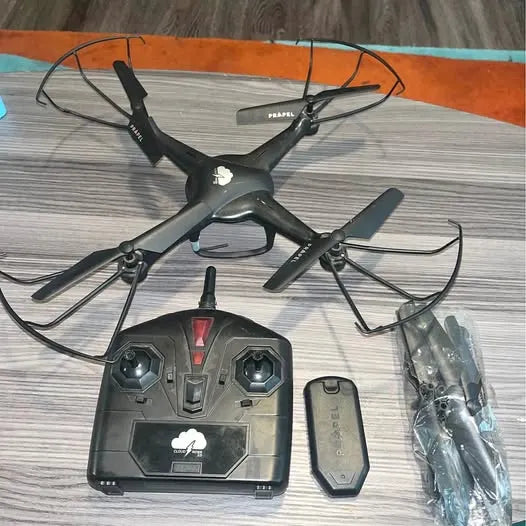 Black quadcopter drone with 4-blade rotors and handheld remote controller