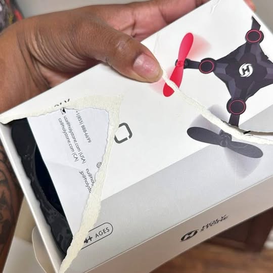 White drone box with illustrated quadcopter, red propellers, and control diagram