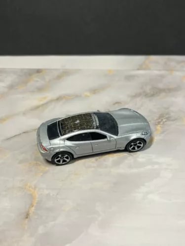 Silver 1/64 diecast model car with black grille and wheels, side view