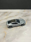 Silver 1/64 diecast model car with black grille and wheels, side view