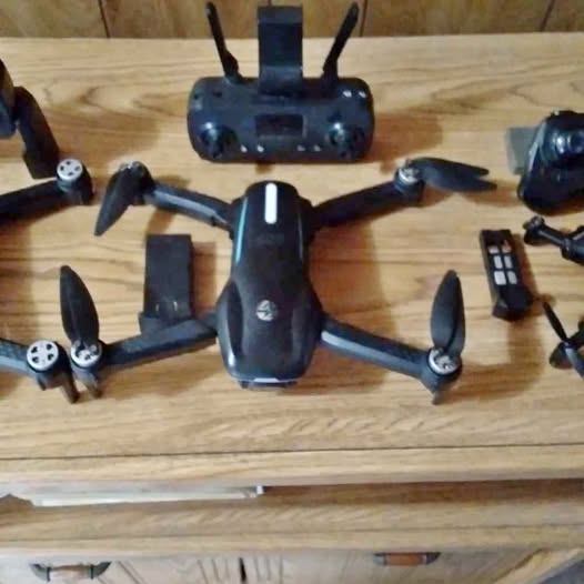 Black quadcopter drone with four propellers and front camera, plus remote controller