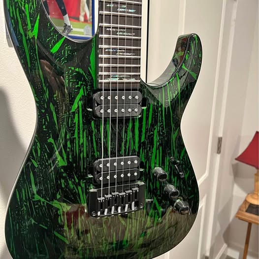Green and black electric guitar with double humbucker pickups and tremolo bridge