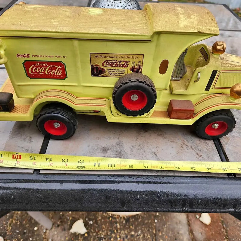 Yellow vintage toy truck with red wheels and Coca-Cola style graphics