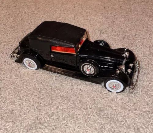 Black diecast model car with red stripe, chrome wheels and detailed grille