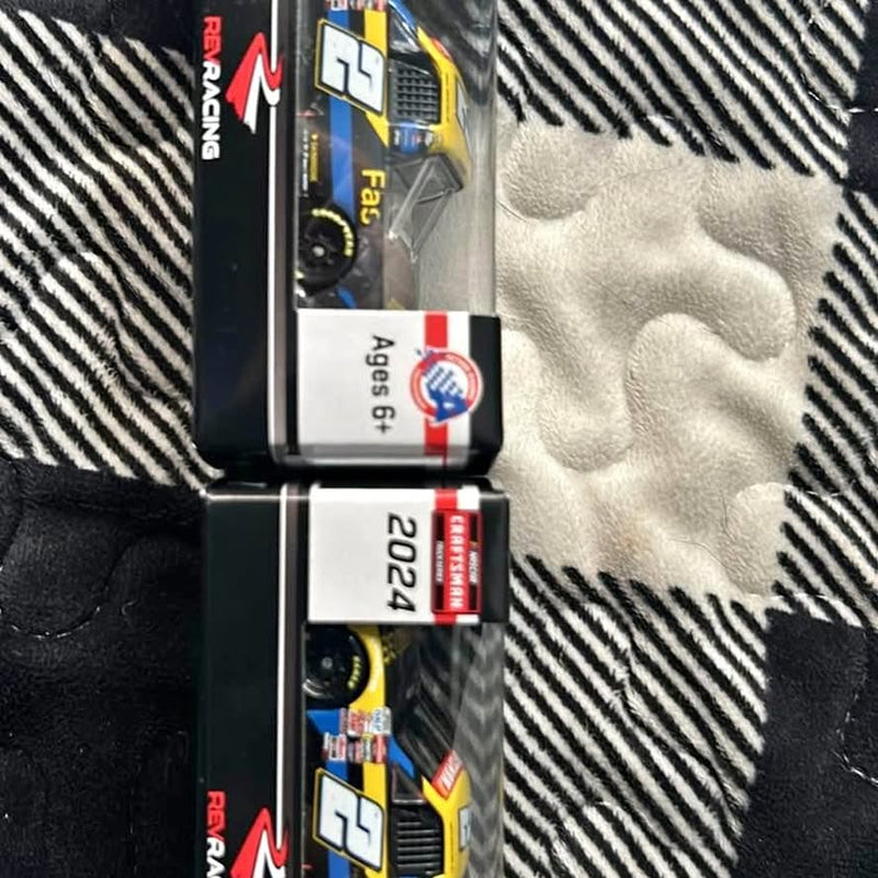Two 1:64 scale diecast trucks in packaging, yellow and black