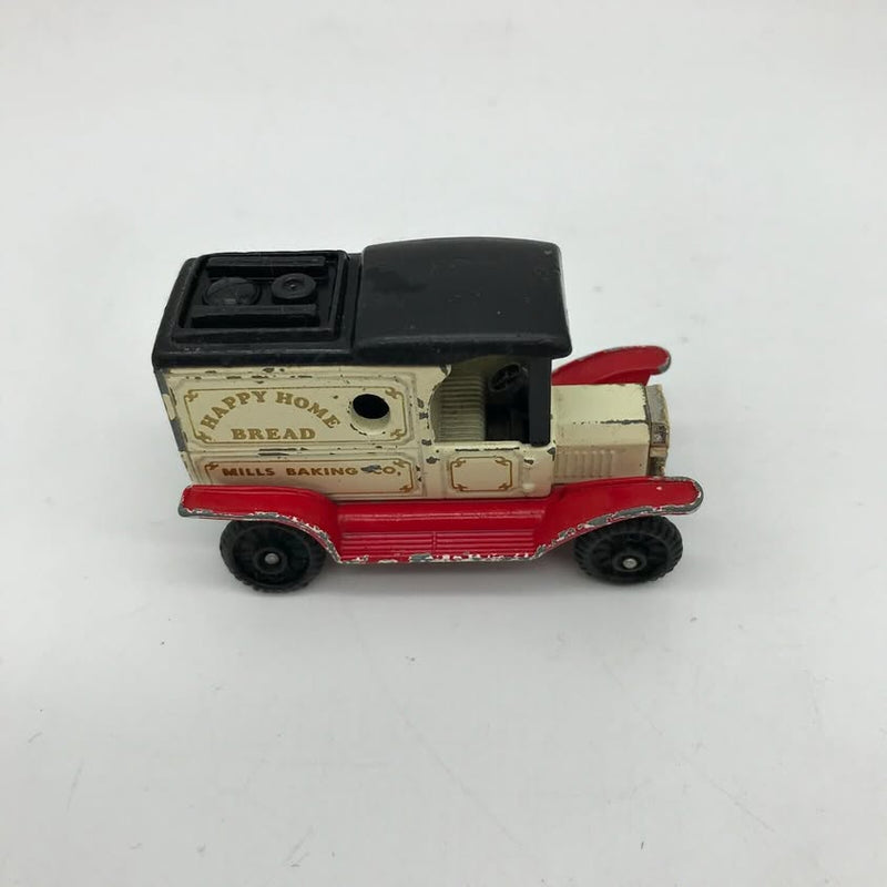 Vintage diecast toy delivery truck with black cab, beige bread body, red base