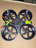 Racing drone with four black propellers, carbon-fiber frame, neon green arms.