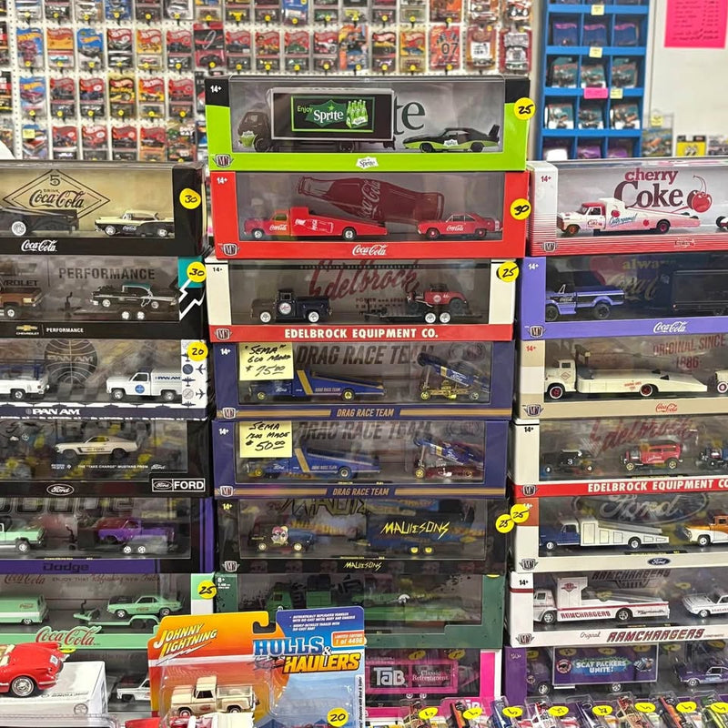 Boxed 1:64 diecast truck, car, and trailer sets collection in display cases