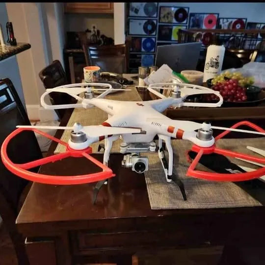 White quadcopter drone with camera and orange prop guards