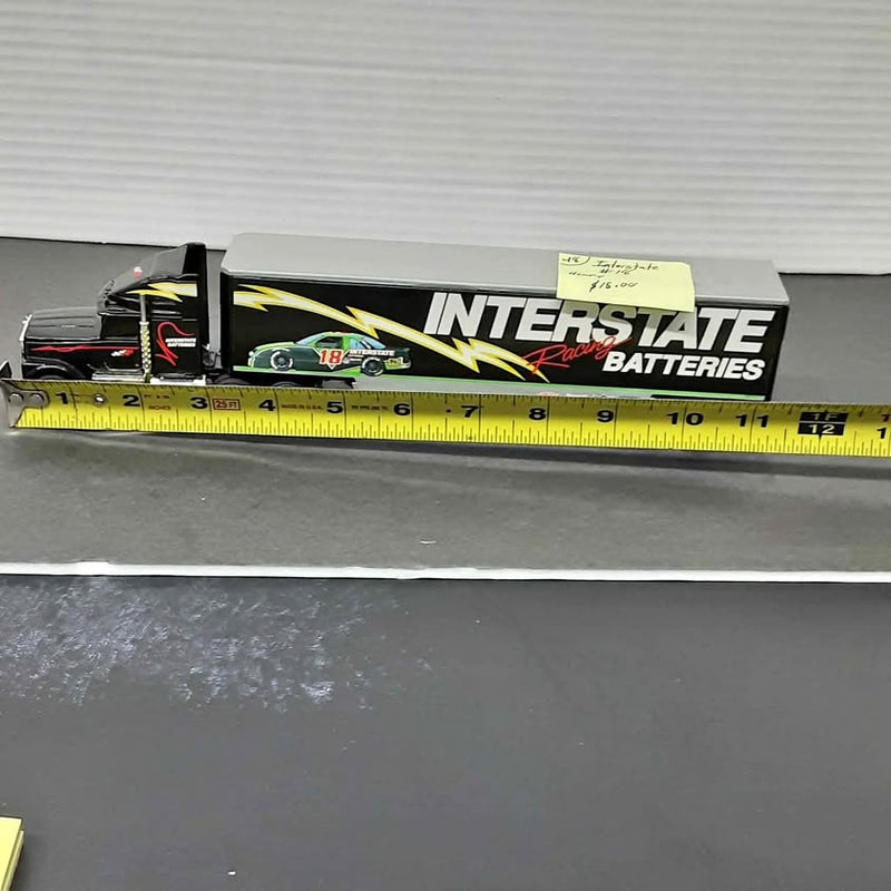 Diecast tractor trailer with black cab and yellow Interstate Batteries graphics, side view.