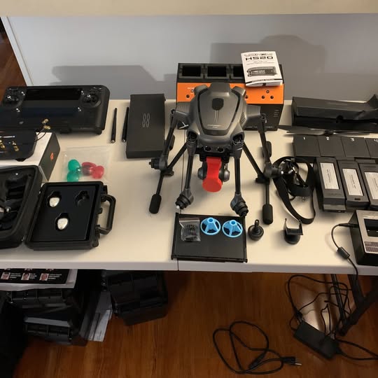 Quadcopter drone with orange and gray frame, prop arms and landing legs