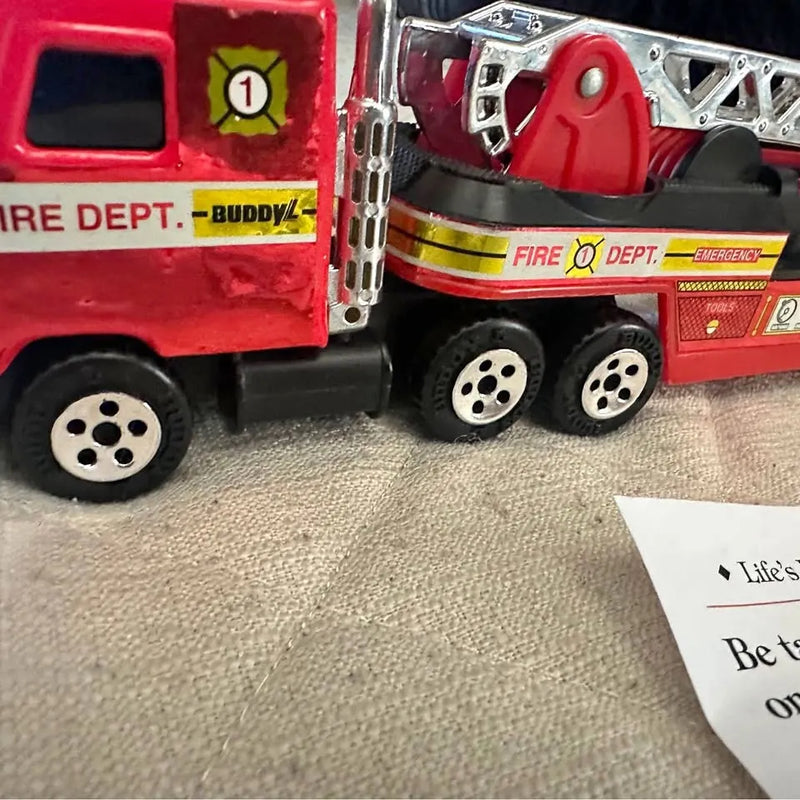Red diecast firetruck toy with silver ladder and detailed wheels