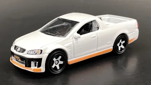 White diecast model ute car with orange side stripe, front three-quarter view