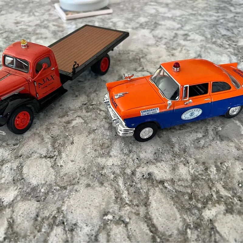 Diecast emergency police car and red truck with open trailer, orange and blue details