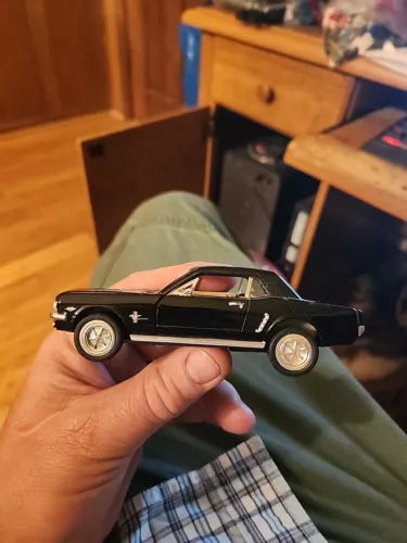 Black diecast model toy car, classic coupe body, side view in hand