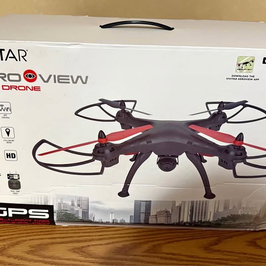 Red and gray quadcopter video drone with four rotors and landing legs