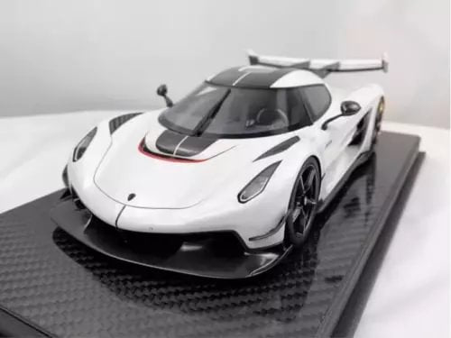 White and black diecast model car with rear wing on dark display base