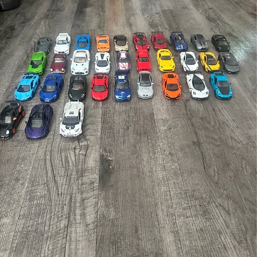 Assorted small diecast cars in multiple colors, various body styles.