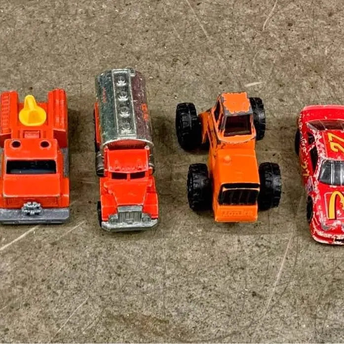 Assorted vintage diecast toy cars in orange, red, silver, and black, multiple models