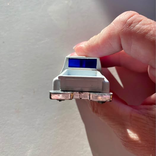 Diecast pickup truck rear close-up, blue bed cap, worn chrome bumper