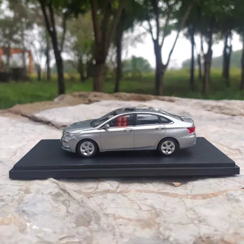 Diecast model car, silver sedan side view on black display base