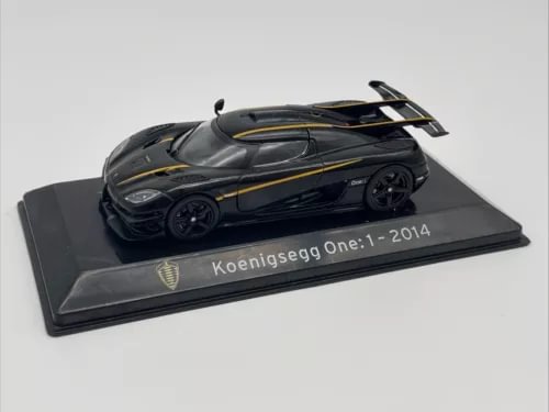Koenigsegg One:1 2014 diecast model car, dark gray with yellow accents, on display base