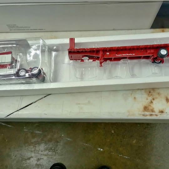 Red diecast dump truck with detailed side body and wheel