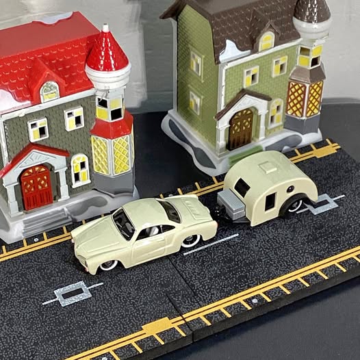 Diecast toy car and track set with two cream cars and small house buildings