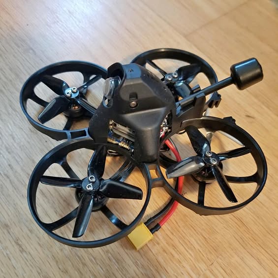 Quadcopter drone with four black propellers and a central metal body