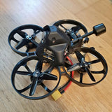 Quadcopter drone with four black propellers and a central metal body