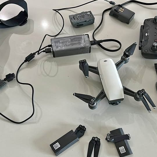 White quadcopter drone with propellers, batteries, and charging adapters