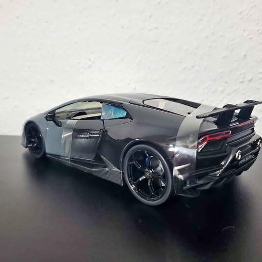 Dark gray diecast sports car with rear spoiler and black wheels, rear three-quarter view