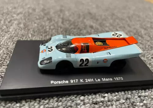 Porsche 917 K diecast model car with orange and white livery, number 22, on display base.