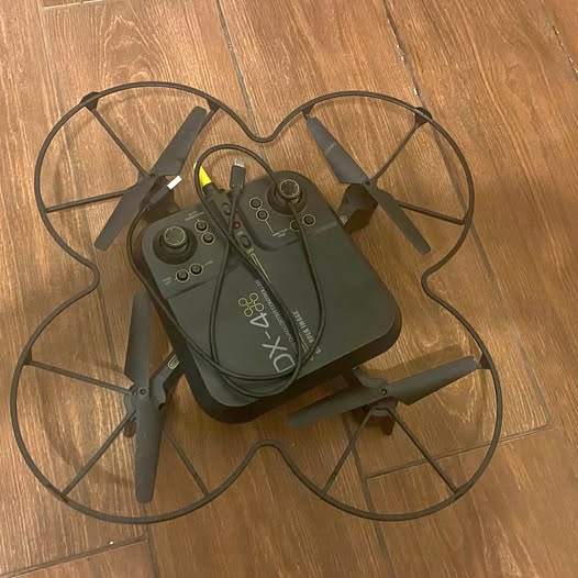 Gray quadcopter drone with remote controller and four propeller arms