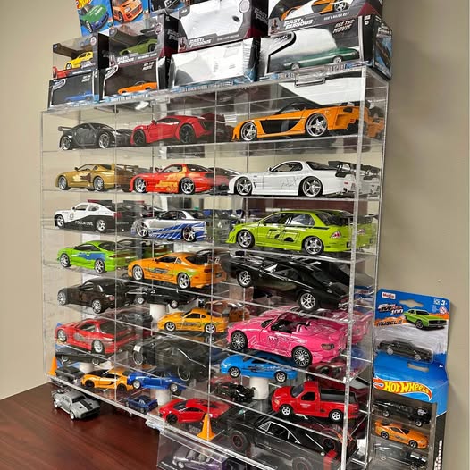 Diecast toy car assortment in clear display case with multiple colorful model cars