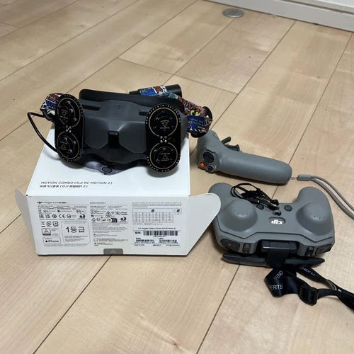 Handheld remote controller with grey body, grip, joystick, and circular control dials
