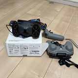 Handheld remote controller with grey body, grip, joystick, and circular control dials