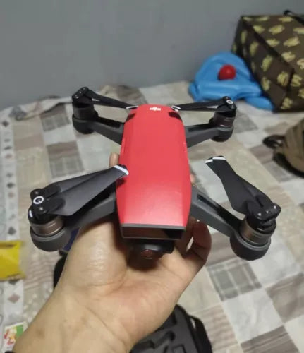 DJI Spark red camera drone with propellers, held in hand