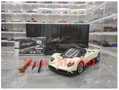 White and black diecast model car with open-roof cockpit detail, on display