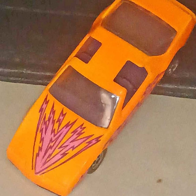 Orange diecast model car with purple lightning graphic and front grille detail