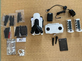 Foldable white quadcopter drone with controller, batteries, and charging accessories