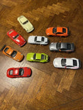 Nine diecast Porsche 911 toy cars in varied colors, top-down view