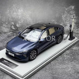 Blue diecast model car on display base with charging port stand, scale replica