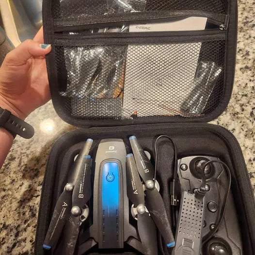 Drone carrying case open with quadcopter arms, remote, and accessories