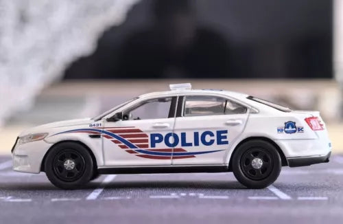 White police diecast sedan toy car with blue stripe and POLICE text, side view.