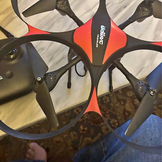 Orange and black quadcopter drone with four propeller arms and camera module