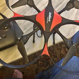 Orange and black quadcopter drone with four propeller arms and camera module